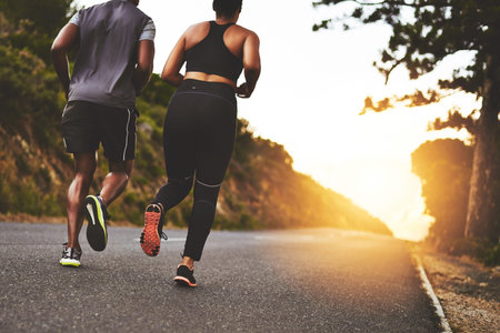 Were in it for the long run. Rearview shot of a young couple out running together.の写真素材