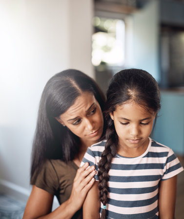 Mommys so sorry. a mother comforting her daughter at home.の写真素材