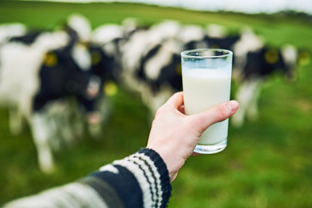 Only the freshest. an unrecognizable man holding a glass of milk on a dairy farm with cattle grazing...