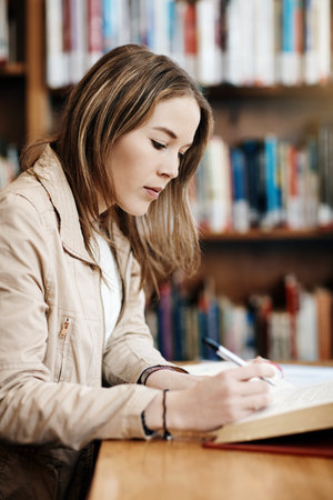 This is second nature for her. a confident young university student working in the library at...