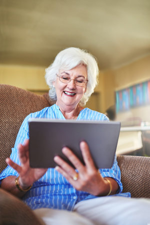 Retirement has become easier with a device like this. a senior woman using a tablet at home.の写真素材