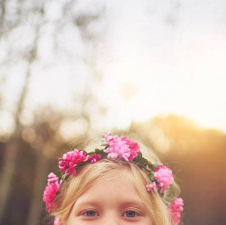 Im down over here. a little girls eyes looking at the camera and hiding while standing outside in nature.の写真素材