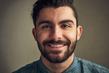 Smiling makes everything seem better. Closeup of a handsome young man posing against a grey background.の写真素材