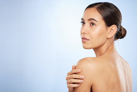 Face, beauty skincare and back of woman in studio isolated on a blue background mockup. Thinking, makeup and natural cosmetics of female model with healthy or glowing skin after spa facial treatmentの写真素材