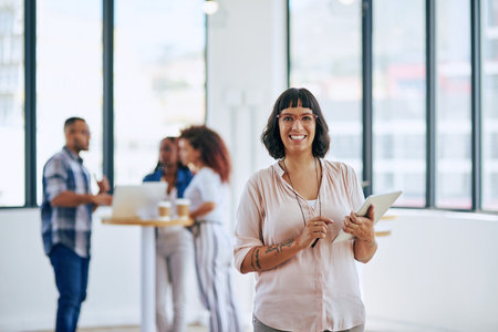 We encourage collaboration in this office. Portrait of a young woman holding a digital tablet in a...