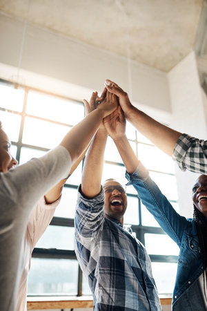 Success, were coming for you. a group of creatives high-fiving in an office.