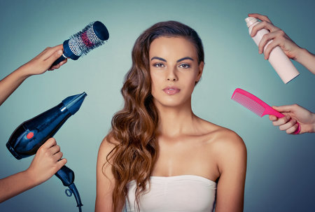 Shes got all the essential tools to create amazing hair. Studio shot of a beautiful young woman posing against a green background.の写真素材