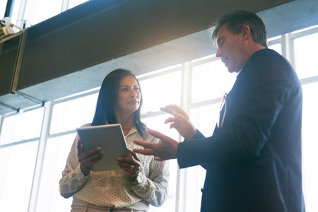 Heres what I was thinking...two businesspeople working together on a digital tablet in an office.