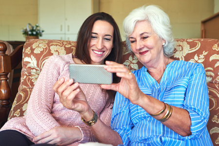Learning all the new tricks. a senior woman and her granddaughter taking a selfie at home.の写真素材