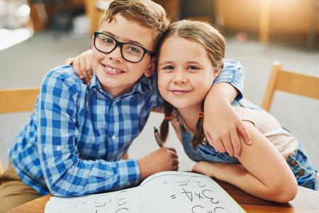 We have been friends for a while. Portrait of two young children working together inside of a classroom during the day.の写真素材