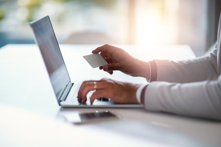 Banking from the comfort of his office. an unrecognizable businessman holding his credit card while using a laptop at his desk.の写真素材