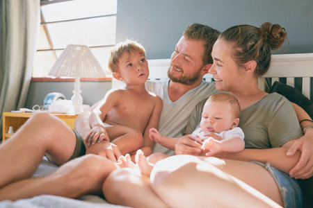 Sunday morning family vibes. a young family of four bonding in the bedroom.の写真素材