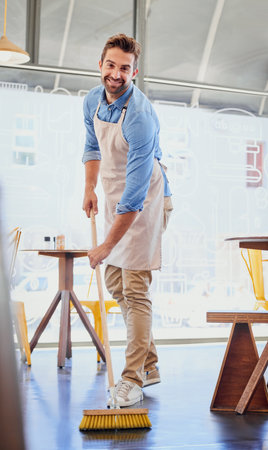The boss isnt afraid to get his hands dirty. Portrait of a happy business owner sweeping the floor in his coffee shop.の写真素材
