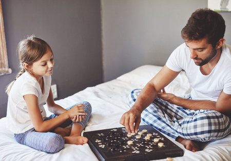 Making the next move. a young father playing a board game with his adorable little daughter at home.