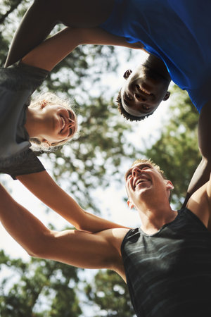 They can rely on each other for constant motivation. Low angle shot of a group of sporty young people standing in a huddle together.の写真素材