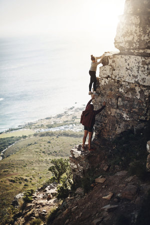 Theyre determined to get to the top. a group of friends scaling the side of a mountain while out for...