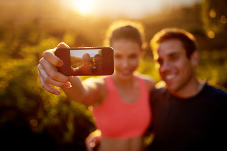 Flaunt your fitness goals. a sporty young couple taking a selfie while out for a run together.の写真素材