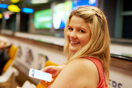 Boarding time is approaching. Portrait of a young woman using a cellphone while sitting in an...