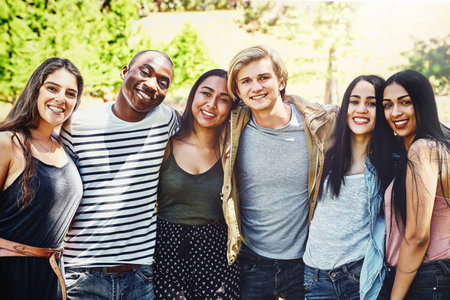 Friendship enriches life. Portrait of a group of happy young friends enjoying a day outdoors.の写真素材