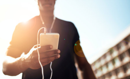 Music motivates him. a sporty young man getting his playlist ready for a run.の写真素材