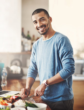 Youre going to want to taste this when Im done. Portrait of a happy young man preparing a healthy meal at home.の写真素材