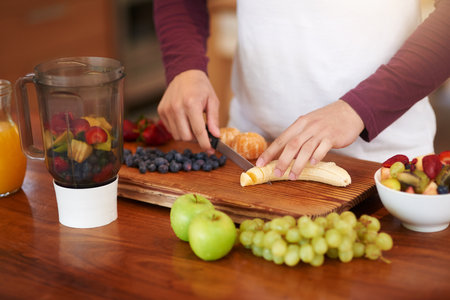 You get out what you put in. an unidentifiable young man preparing a healthy breakfast of fruit in his kitchen at home.の写真素材