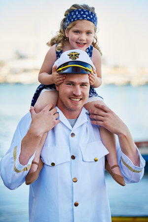 Shes got me wrapped around her finger. Portrait of a father in a navy uniform carrying his little girl on his shoulders.の写真素材