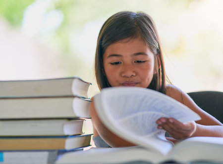 Shes a big bookworm. a little girl reading a book at home.の写真素材