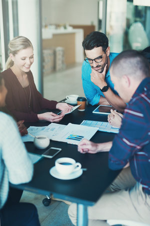 Gathered around the meeting table. High angle shot of a group of businesspeople meeting in the boardroom.の写真素材