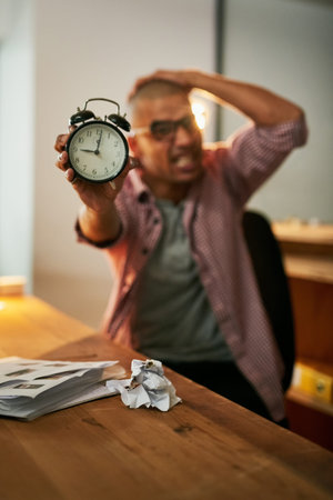 Ill never get done in time. Portrait of a young designer holding an alarm clock and looking stressed...
