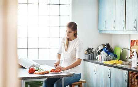 Youll never regret a healthy meal. a young woman preparing a healthy meal at home.の写真素材