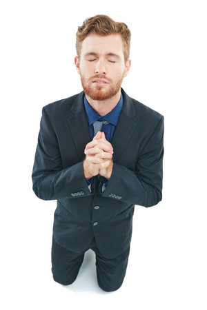 Praying for a miracle. Studio shot of a handsome young businessman with his hands together in prayer against a white background.の写真素材