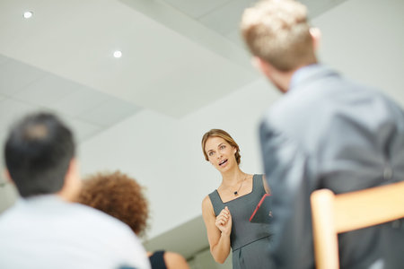 She has everyones attention. a businesswoman holding a digital tablet while giving a presentation to...