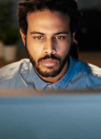 Focus on being productive instead of busy. a young designer working late on a computer in an office.の写真素材
