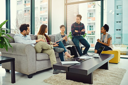 They share a common vision for success. a group of colleagues having a discussion in an office.