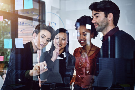 Their success is in their ability to plan. a group of businesspeople working on a glass wall the...