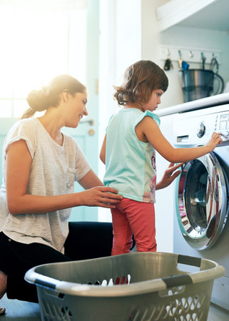 We enjoy doing the chores together. a little girl helping her mother with the washing.の写真素材