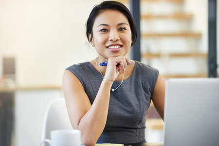 Im moving this company towards success. Portrait of a confident young businesswoman working on a laptop in a modern office.の写真素材