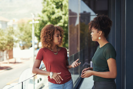 Build a healthy relationship with your coworkers. two businesswomen chatting outside on a balcony.の写真素材
