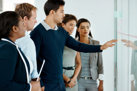 Strategy in action. a group of businesspeople strategizing on a glass wipe board in their office.の写真素材