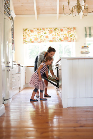 Baked with love. a little girl baking with her mother in the kitchen.の写真素材