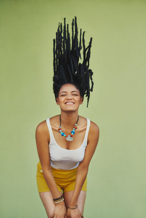 Hair goals. Studio shot of an attractive young woman tossing her hair against a green background.の写真素材
