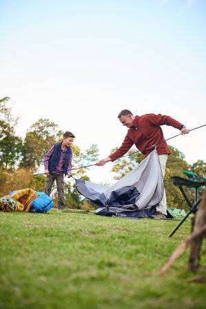Hes a great little helper. a father and son setting up a tent together while camping.の写真素材