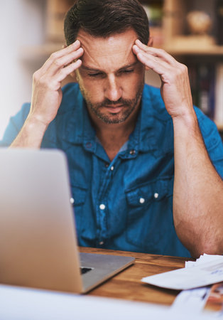 Feeling a little bit overworked. a businessman looking stressed while working at home.