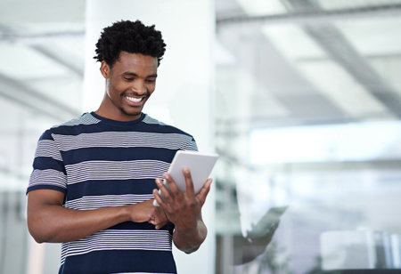 Getting creative. a young businessman using his tablet in the office.