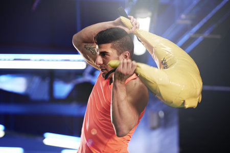 His workout is in full swing. a young man working out with a sandbag at the gym.の写真素材