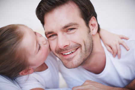 Expressing her love for her Dad. A cute little girl giving her dad a kiss on the cheek.の写真素材