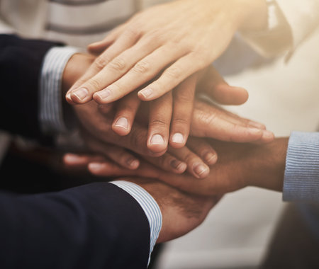 Together we can build an empire. a group of businesspeople putting their hands together in unity.