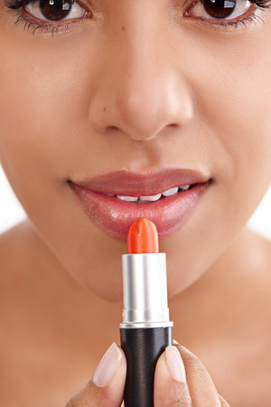 Luscious lips. Closeup studio shot of a beautiful young woman putting on lipstick.の写真素材