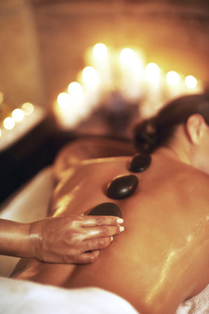 Get a hot stone massage. a young woman getting a hot stone massage.の写真素材